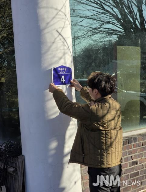 군 행복민원과 직원이 도로명주소 건물번호를 직접 배달하며 부착하고 있다.