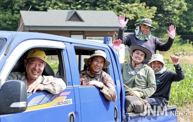 괴산군 계절근로자 프로그램을 통해 배치된 외국인 근로자들이 옥수수밭 앞에서 단체사진을 찍으며 농번기 현장의 활력을 보여주고 있다.